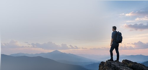 A founder standing at the top of a mountain, looking toward the horizon